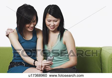 Close-up of two young women operating a mobile phone View Large Photo Image Stock Image - Close-up of two young women operating a mobile phone. Fotosearch