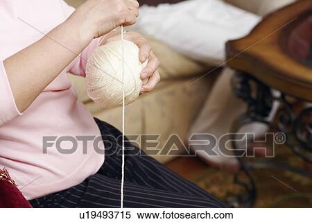 Stock Photography - Mid section view of a senior woman holding a ball of wool. Fotosearch