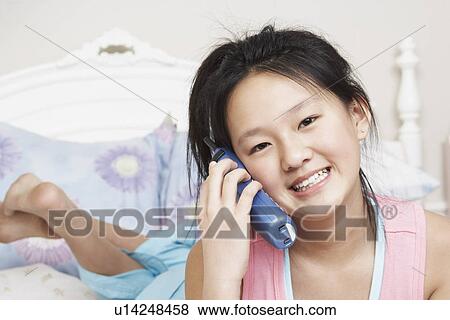 Stock Photo - Portrait of a girl using a cordless telephone. Fotosearch