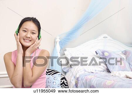 Stock Photo - Portrait of a girl wearing headphones listening to music. Fotosearch