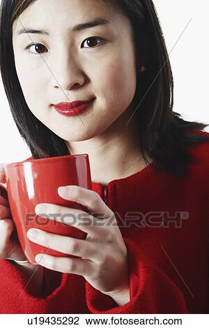 Stock Image - Portrait of a young woman holding a coffee cup. Fotosearch