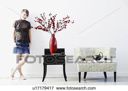 Stock Photo - Portrait of a young woman leaning against a wall. Fotosearch