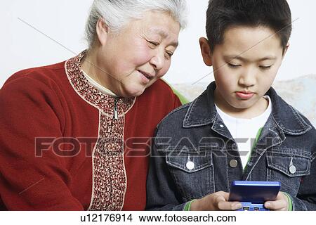 Close-up of a boy and his grandmother playing a video game View Large Photo Image Picture - Close-up of a boy and his grandmother playing a video game. Fotosearch