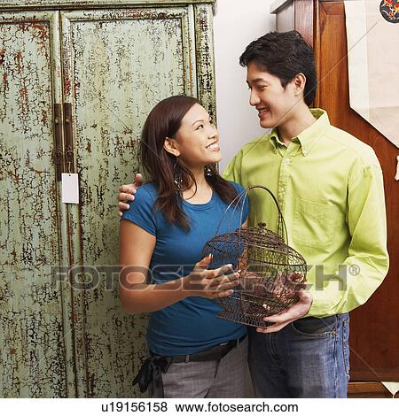 Close-up of a young couple holding a cage and looking at each other View Large Photo Image Stock Photo - Close-up of a young couple holding a cage and looking at each other. Fotosearch