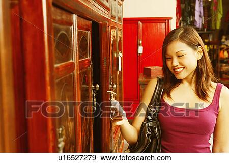 Stock Photo - Close-up of a young woman looking at a price tag and smiling. Fotosearch