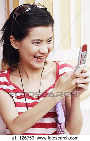 Stock Photo - Close-up of a young woman operating a mobile phone. Fotosearch