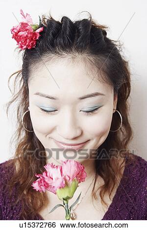 Stock Photograph - Close-up of a young woman smelling a flower. Fotosearch