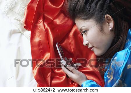 Stock Image - High angle view of a young woman looking at a mobile phone. Fotosearch
