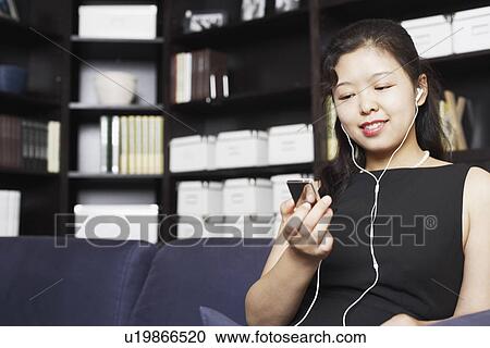Low angle view of a young woman listening to music on headphones smiling View Large Photo Image Stock Image - Low angle view of a young woman listening to music on headphones smiling. Fotosearch
