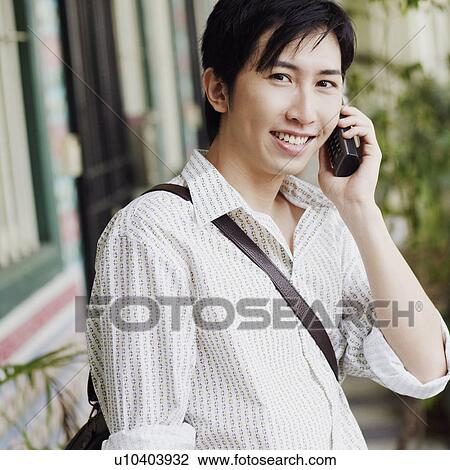 Stock Image - Portrait of a young man talking on a cordless phone. Fotosearch