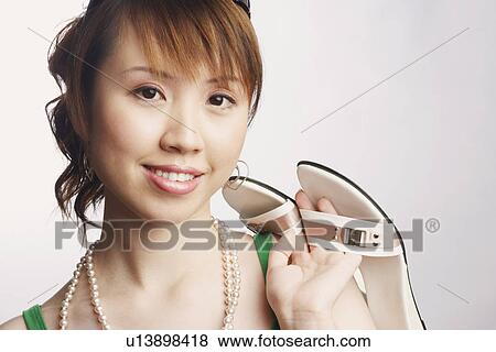 Portrait of a young woman holding a pair of slipper and smiling View Large Photo Image Stock Photo - Portrait of a young woman holding a pair of slipper and smiling. Fotosearch