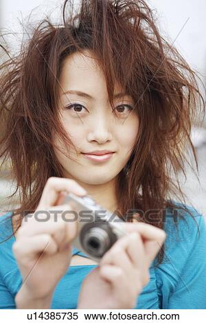 Stock Photography - Portrait of a young woman holding a digital camera. Fotosearch