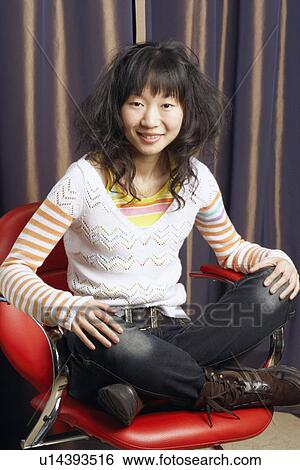 Portrait of a young woman sitting on an armchair smiling View Large Photo Image Stock Photograph - Portrait of a young woman sitting on an armchair smiling. Fotosearch