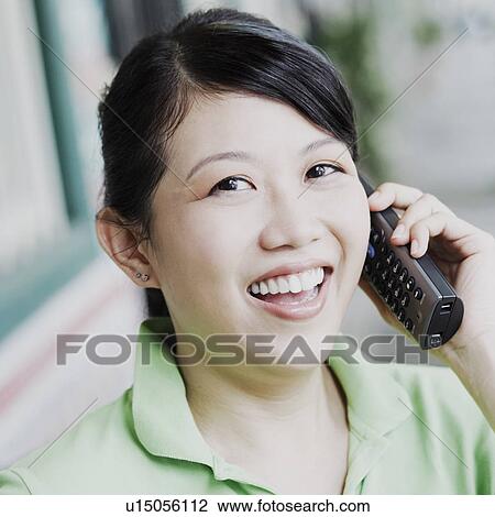 Portrait of a young woman talking on a cordless phone View Large Photo Image Stock Image - Portrait of a young woman talking on a cordless phone. Fotosearch