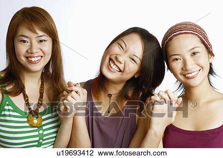 Stock Image - Portrait of three young women posing and smiling. Fotosearch
