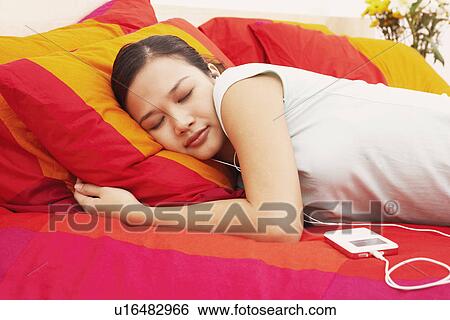 Stock Photograph - Side profile of a young woman sleeping on the bed. Fotosearch