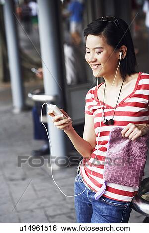 Close-up of a young woman smiling and listening to music View Large Photo Image Stock Photograph - Close-up of a young woman smiling and listening to music. Fotosearch