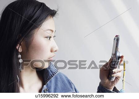 Stock Image - Close-up of a young woman using a mobile phone. Fotosearch