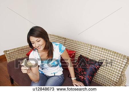 Stock Image - High angle view of a young woman holding a home video camera and smiling. Fotosearch
