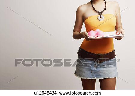 Picture - Mid section view of a young woman holding a serving tray. Fotosearch