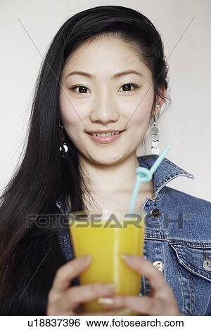 Portrait of a young woman holding a glass of juice View Large Photo Image Stock Photograph - Portrait of a young woman holding a glass of juice. Fotosearch