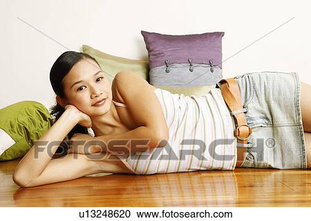 Stock Image - Portrait of a young woman lying on a hardwood floor. Fotosearch