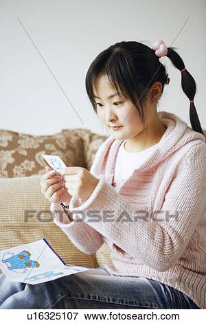 Stock Photo - Side profile of a young woman doing embroidery. Fotosearch