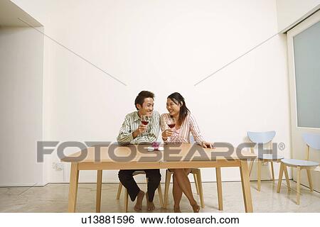 Young couple holding glasses of wine and looking at each other View Large Photo Image Stock Photograph - Young couple holding glasses of wine and looking at each other. Fotosearch