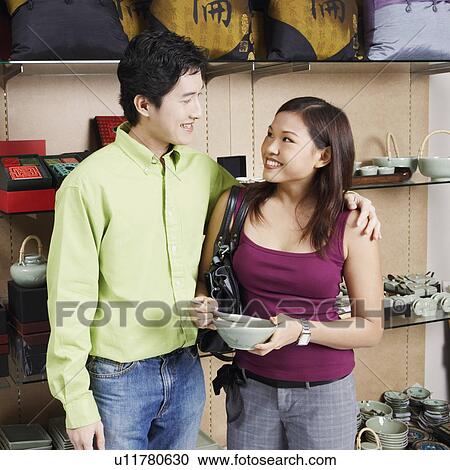 Stock Image - Young couple looking at each other and smiling in a store. Fotosearch