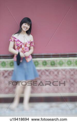 Picture - Young woman leaning against a wall. Fotosearch