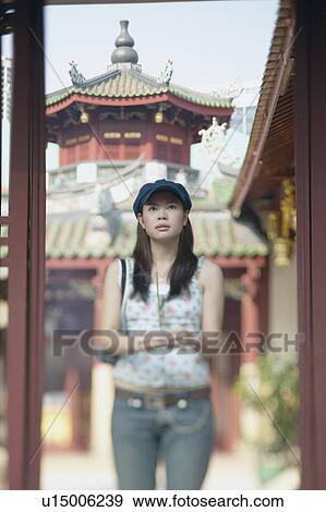 Stock Photo - Young woman standing in front of a pagoda temple. Fotosearch