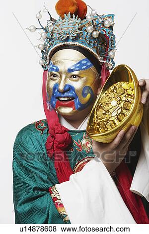 Stock Photo - Close-up of a male Chinese opera performer holding a bowl full of gold coins. Fotosearch