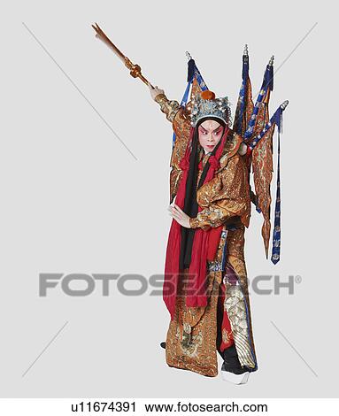 Stock Image - Male Chinese opera performer gesturing with a weapon. Fotosearch