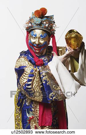 Stock Image - Portrait of a male Chinese opera performer holding a bowl full of gold coins. Fotosearch