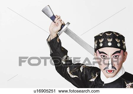 Stock Image - Portrait of a male Chinese opera performer holding a weapon. Fotosearch