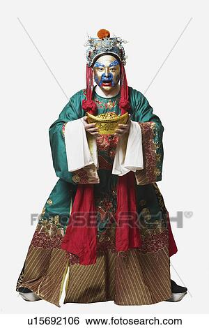 Stock Photograph - Portrait of a male Chinese opera performer holding a bowl full of gold coins. Fotosearch