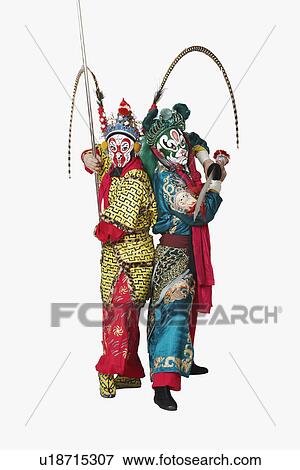 Stock Photo - Side profile of two male Chinese opera performers gesturing with weapons. Fotosearch