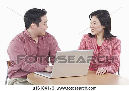 Stock Image - Close-up of a businessman and a businesswoman using a laptop. Fotosearch