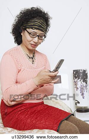 Stock Photograph - Close-up of a mature woman using a mobile phone. Fotosearch