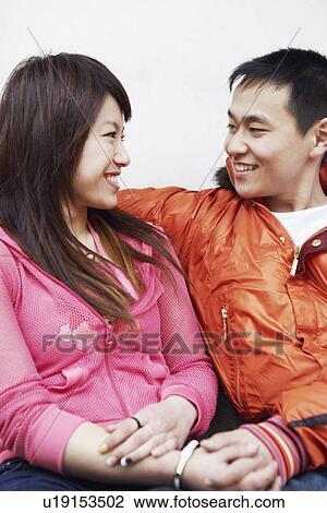 Stock Image - Close-up of a young couple looking at each other smiling. Fotosearch