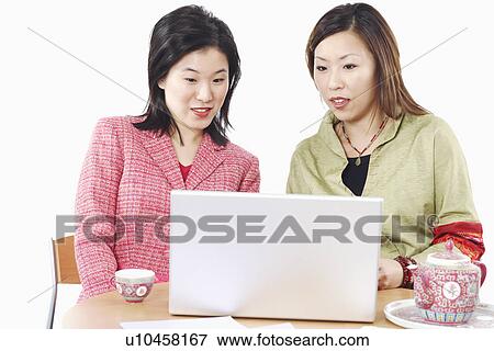 Stock Photo - Close-up of two businesswomen using a laptop. Fotosearch
