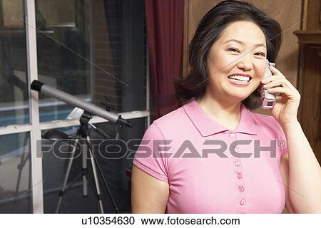 Stock Image - Portrait of a mature woman talking on a cordless telephone. Fotosearch