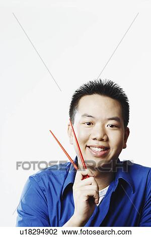 Portrait of a young man holding chopsticks View Large Photo Image Stock Image - Portrait of a young man holding chopsticks. Fotosearch