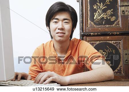 Portrait of a young man using a computer View Large Photo Image Stock Photo - Portrait of a young man using a computer. Fotosearch
