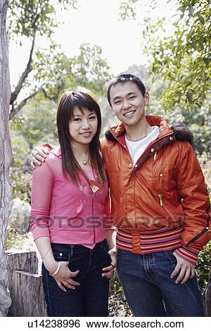 Portrait of a young man with his arm around a young woman smiling View Large Photo Image Stock Photograph - Portrait of a young man with his arm around a young woman smiling. Fotosearch