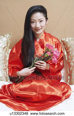 Stock Photo - Portrait of a young woman holding a bunch of flowers. Fotosearch
