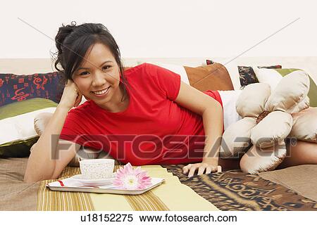 Portrait of a young woman lying on the bed and smiling View Large Photo Image Stock Photography - Portrait of a young woman lying on the bed and smiling. Fotosearch