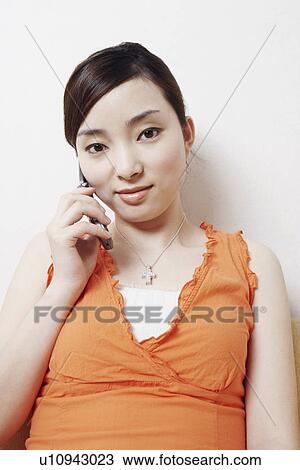 Stock Image - Portrait of a young woman using a mobile phone. Fotosearch