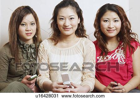 Portrait of three young women sitting together smiling View Large Photo Image Stock Image - Portrait of three young women sitting together smiling. Fotosearch