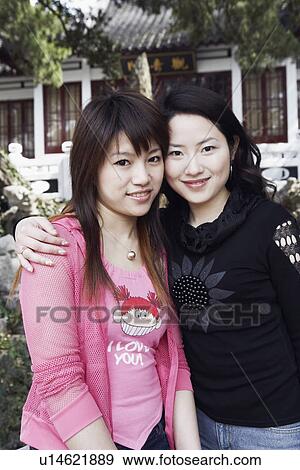Stock Photo - Portrait of two young women standing together smiling. Fotosearch